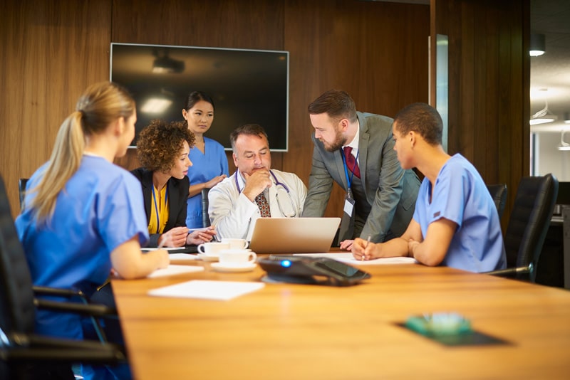 medical team look at laptop in board room
